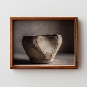 Puede incluir: Imagen enmarcada de un cuenco de cerámica artesanal y agrietado. El cuenco es de color beige claro con grietas marrones oscuras y un borde oscuro. El marco es de madera.