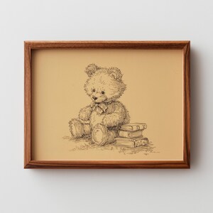 May include: A framed pen and ink drawing of a teddy bear sitting next to a stack of books. The artwork features a brown wooden frame and a tan background. The teddy bear has a bow tie.