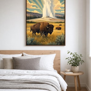 May include: A framed wall art print featuring a large brown bison standing in a golden grassy field. In the background, a geyser erupts with a tall plume of white steam against a blue sky with sun rays. Two smaller bison are visible in the distance.