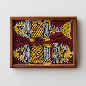 May include: A framed artwork featuring two stylized fish. The fish are primarily yellow with intricate black and white patterns, set against a deep red background. The artwork is enclosed in a brown wooden frame.