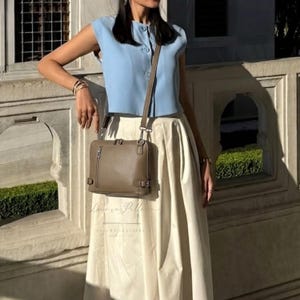 Bolso bandolera rectangular de piel color topo con correa ajustable, un clásico para el día a día.