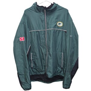 May include: Green and black zip-up jacket with the Green Bay Packers logo on the chest. Features the Sports Illustrated logo on the left sleeve. The jacket has white trim and two front pockets.