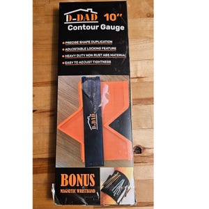 May include: A D-DAD 10" contour gauge in a box. The gauge is orange and black, designed for precise shape duplication. Features include an adjustable locking feature and heavy-duty, non-rust ABS material. The box also includes a bonus magnetic wristband.