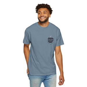 Könnte beinhalten: Blaues T-Shirt mit einer Tasche mit einem Kaffeetassen-Design und dem Text "LET'S GO FORWARD". Das Design beinhaltet Dampf, der aus der Tasse aufsteigt. Das Shirt ist aus weichem Material.
