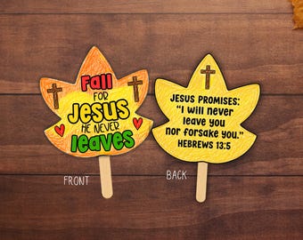 May include: Two leaf-shaped paper cutouts on wooden sticks. The front is orange and yellow with the text 'Fall for Jesus He Never Leaves', two brown crosses, and two red hearts. The back is yellow with a brown cross and the text 'Jesus Promises: I will never leave you nor forsake you. Hebrews 13:5'.