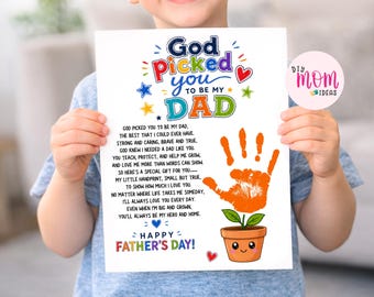 May include: A colorful Father's Day print held by a child. The print features the text "God picked you to be my Dad" with a handprint and a smiling plant pot illustration. The words "Happy Father's Day!" are also included.