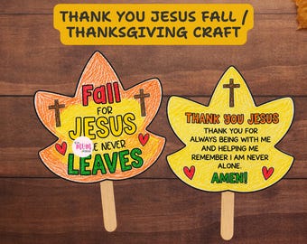 May include: Two leaf-shaped paper crafts on wooden sticks. The orange leaf features the text Fall FOR JESUS HE NEVER LEAVES with two crosses and two red hearts. The yellow leaf features the text THANK YOU JESUS THANK YOU FOR ALWAYS BEING WITH ME AND HELPING ME REMEMBER I AM NEVER ALONE. AMEN! with a cross and two red hearts.
