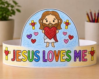 May include: A paper crown featuring a colored illustration of Jesus holding a large red heart. The background is blue with small hearts and yellow crosses. The band displays the text JESUS LOVES ME in multicolored letters with yellow crosses and red hearts.