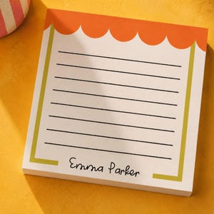 May include: A square notepad with a white background, featuring a scalloped orange top border and thin olive green vertical side lines. The notepad contains black horizontal lines for writing and the printed name Emma Parker at the bottom.
