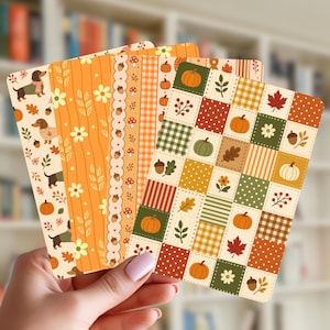 May include: A set of four rectangular bookmarks featuring autumn-themed patterns. Designs include dachshunds with scarves, orange floral stripes, acorn borders, and a patchwork grid of pumpkins, leaves, flowers, and plaid squares in fall colors.
