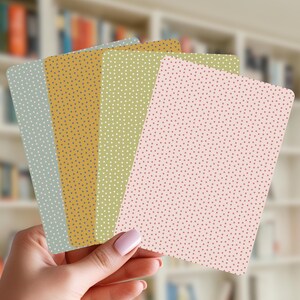 May include: A set of four rectangular cards with rounded corners, each featuring a distinct solid background color—muted blue, mustard yellow, olive green, and soft pink—all covered in a uniform pattern of small, contrasting polka dots.