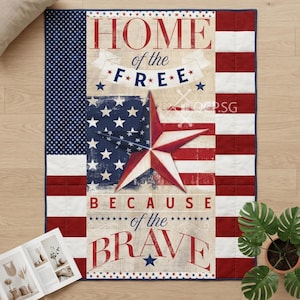 May include: A patriotic quilt with an American flag design, a large star, and the text "HOME of the FREE BECAUSE of the BRAVE." The quilt has a blue border and is decorated with red, white, and blue colours.