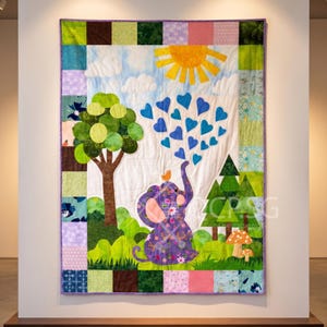 May include: A rectangular quilt featuring a purple floral elephant with a small orange bird on its head, blowing blue hearts into the air. The scene includes a green tree, pine trees, a yellow sun, and mushrooms, all framed by a colorful patchwork border.