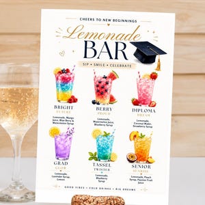 May include: A colorful sign for a lemonade bar, featuring six different lemonade recipes with names like "Bright Future" and "Diploma Dream." The sign includes a graduation cap graphic and the words "Cheers to New Beginnings."