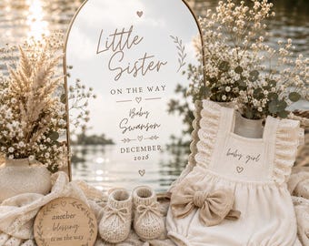 Może przedstawiać: Łukowaty znak lustrzany z napisem Little Sister ON THE WAY Baby Swanson DECEMBER 2026, kremowe body niemowlęce z falbankami i kokardą, para dzianinowych bucików oraz okrągła drewniana tabliczka z napisem another blessing is on the way.