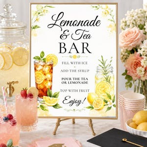 Puede incluir: Un letrero con marco dorado con las palabras "Lemonade & Tea Bar" e instrucciones para preparar las bebidas. La imagen incluye vasos de té helado y limonada, fruta fresca y un birrete.