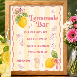 May include: A framed sign with a vintage design for a lemonade bar. The sign features a yellow and white striped background, pink accents, and illustrations of lemons and drinks. Text includes "Lemonade Bar" and instructions.