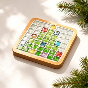 Puede incluir: Un posavasos cuadrado de madera con un mosaico de pequeñas baldosas cuadradas y brillantes. Las baldosas están dispuestas en un patrón de cuadrícula y muestran una variedad de colores, incluyendo tonos verdes, vidrio transparente, rojo, azul y amarillo.