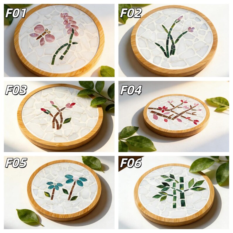 May include: A collection of six round coasters with mosaic designs. Each coaster features a different floral or botanical pattern in various colors, set within a white mosaic background and a natural wood frame. Designs include flowers, butterflies, and bamboo.