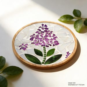 Puede incluir: Posavasos redondo de madera con dise&ntilde;o floral de mosaico. Presenta una flor morada con hojas verdes y fondo blanco. Di&aacute;metro: 15,5 cm.
