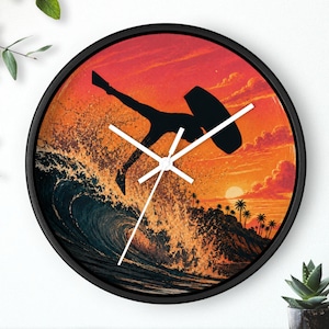 May include: A round wall clock with a black frame featuring a graphic print of a silhouette of a person surfing a large wave against a vibrant orange and red sunset sky with palm trees. The clock has white hour, minute, and second hands.