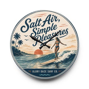 May include: A round wall clock featuring a vintage-style illustration of a surfer on a wave at sunset with palm trees. The text reads Salt Air, Simple Pleasures and Glory Daze Surf Co. The clock has black hands and a cream, blue, and orange color palette.