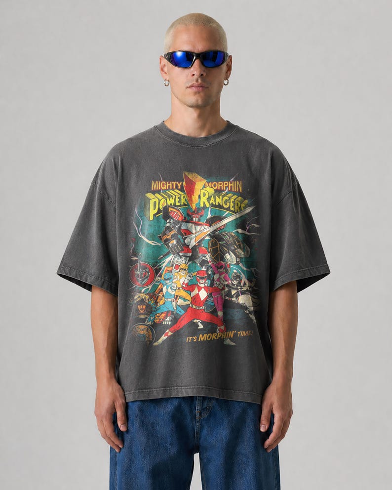K&ouml;nnte beinhalten: Dunkelgraues T-Shirt mit einer Grafik der Mighty Morphin Power Rangers. Das Design umfasst das Power Rangers-Team, einen Megazord und den Text "Mighty Morphin Power Rangers" und "It's Morphin' Time!"