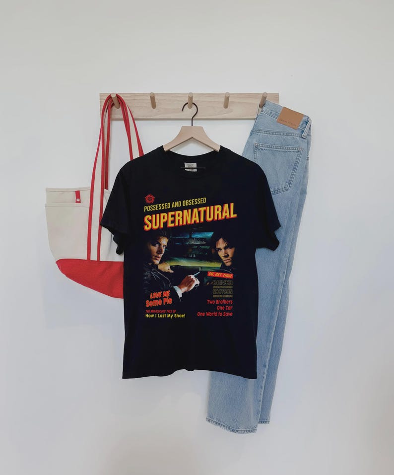 May include: A black short-sleeve t-shirt featuring a graphic print with the text "POSSESSED AND OBSESSED SUPERNATURAL" and images of two men. The print includes additional text: "LOVE ME Some Pie", "How I Lost My Shoe!", "Two Brothers One Car One World to Save".