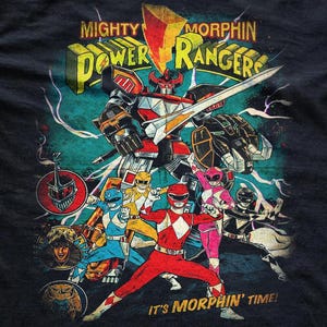 High-detail close-up of a vintage Mighty Morphin Power Rangers graphic print. Features the Megazord and all five Rangers in a distressed, retro comic style with vibrant colors and a weathered texture on soft, dark cotton fabric.