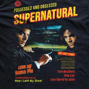 May include: A black t-shirt featuring a graphic print of two men in a car at night. Text includes POSSESSED AND OBSESSED SUPERNATURAL, LOVE ME SOME PIE, THE MIRACULOUS TALE OF HOW I LOST MY SHOE, SO, GET THIS! DRIVER PICKS THE MUSIC, SHOTGUN SHUTS HIS CAKEHOLE.