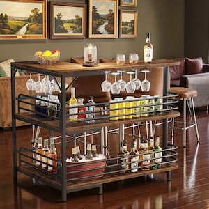 May include: A multi-tiered wooden bar cart with a dark metal frame, featuring hanging glass racks, three shelves for bottles and cans, and a top surface holding a fruit bowl and a glass lamp. The cart is stocked with various liquor bottles.
