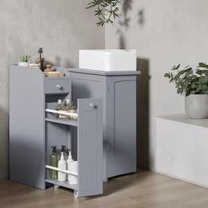 May include: A grey bathroom storage cabinet with a pull-out drawer and a sliding shelf unit on wheels. The unit features a top drawer with a silver knob, two open shelves with white safety rails for bottles, and a matching grey cabinet with a door.