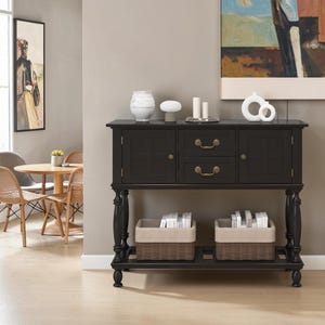 May include: A black wooden console table featuring two side cabinets with square panel detailing, two central drawers with brass-toned pulls, and a lower shelf holding two rectangular woven baskets with light-colored fabric liners.