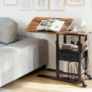May include: A mobile side table with a rustic brown wood-grain finish and a black metal frame. It features an adjustable tilting top, a smaller fixed side shelf, a black fabric storage drawer, and a lower shelf holding several upright books.