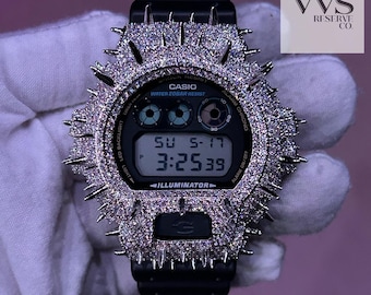 May include: Black Casio digital watch with a diamond-encrusted bezel and band. The watch face displays the date and time. The watch has a black band and a silver-colored bezel with pointed edges. The watch is water resistant.