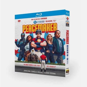 May include: Blu-ray box set for the TV series "Peacemaker" Season 2. The cover features a group of costumed characters in front of a brick wall. The title "Peacemaker" is in large, bold letters. The text "In What World Are They?" is also visible.