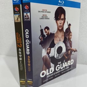 May include: Two Blu-ray disc cases for "The Old Guard" film. The cover features Charlize Theron and other actors. The spines have Japanese text and the title. The cases are blue and white with the Blu-ray logo.