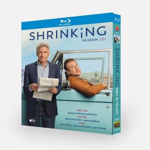 May include: Blu-ray box set for the TV series "Shrinking: Season 3". The cover features two actors in front of a light blue car. The title is in large white letters with the season number. The box has a blue top.