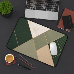 May include: A rectangular desk mat featuring a geometric pattern of dark green, sage green, beige, and white marble-like sections separated by thin gold lines. The mat has a black border and is positioned on a dark surface with a white computer mouse.