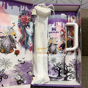 May include: A gift set featuring a Stanley mug and tumbler with a matching straw and carrying bag. The set has a purple and white color scheme with a spooky cartoon design. The box has a matching design with the text "AuroraCreations".