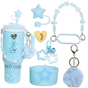 Pu&ograve; includere: Un bicchiere azzurro con accessori, tra cui un coperchio a forma di stella, un cinturino di perline e un portachiavi soffice. Il bicchiere ha un design a stella e il testo "NO cup". Sono inclusi accessori aggiuntivi.