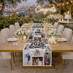 May include: A long wooden table set for a graduation celebration, adorned with a photo collage table runner. The runner features photos and the text "2026 Congratulations". The scene includes white flowers, candles, and the word "Congrats" in neon.
