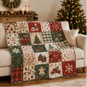 May include: A quilted throw blanket featuring a patchwork design with alternating squares in red, green, and cream. The pattern includes illustrations of Christmas trees, stockings, gingerbread men, red trucks, houses, and snowflakes on a fabric surface.