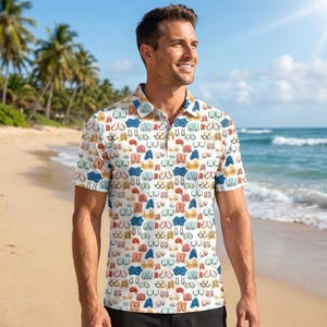 May include: A short-sleeved polo shirt with a white background and a repeating pattern of colorful, stylized breasts. The shirt has a collared neckline and is worn by a person on a beach.
