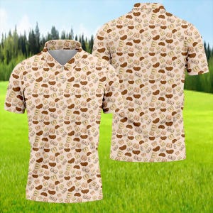 May include: A short-sleeved polo shirt with a beige background and a repeating pattern of brown and tan breast shapes. The shirt has a collared neckline and a button-down front. The background is a green field with trees.