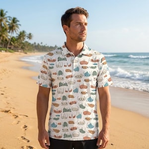 May include: White polo shirt with a repeating pattern of stylized breasts in various colors. The shirt has short sleeves and a collared neckline. The background shows a beach with palm trees and ocean waves.