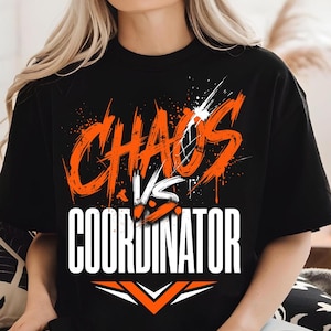 Puede incluir: Camiseta negra de cuello redondo con las palabras "CHAOS" en letras grandes y desgastadas de color naranja sobre "VS" y "COORDINATOR" en letras blancas. Un diseño de galón en la parte inferior.