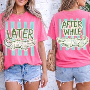 Puede incluir: Camisetas rosas con un gráfico de cocodrilo verde y las palabras "LATER" y "AFTER WHILE". Las camisetas tienen rayas verticales turquesas y se combinan con pantalones cortos de mezclilla. Las camisetas son de estilo casual.