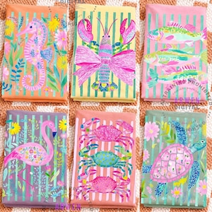 May include: Six colorful, patterned fabric squares featuring sea creatures. Designs include a seahorse, lobster, fish, flamingo, crabs, and a sea turtle. Each design is set against a striped background with floral accents. The color palette includes pink, orange, yellow, and green.