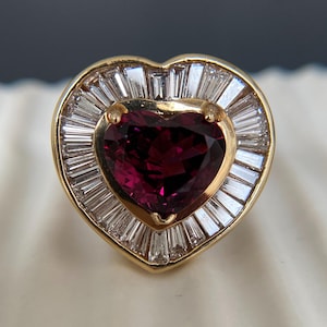 Anel em formato de coração com rubi, halo de diamantes em lapidação baguete, joia marcante em ouro amarelo.